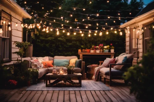 Cozy small patio with outdoor sofa set and coffee table under warm string lights on a wooden deck at dusk. - shupix