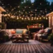 Cozy small patio with outdoor sofa set and coffee table under warm string lights on a wooden deck at dusk. - shupix